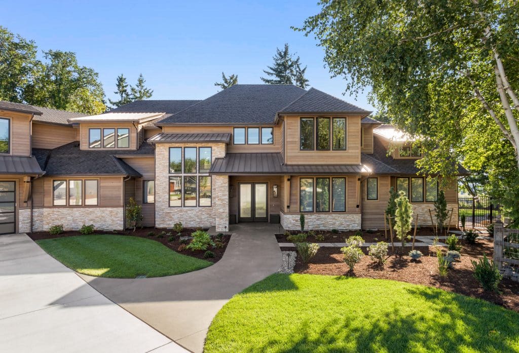 Facade of home with manicured lawn, and backdrop of trees and blue sky